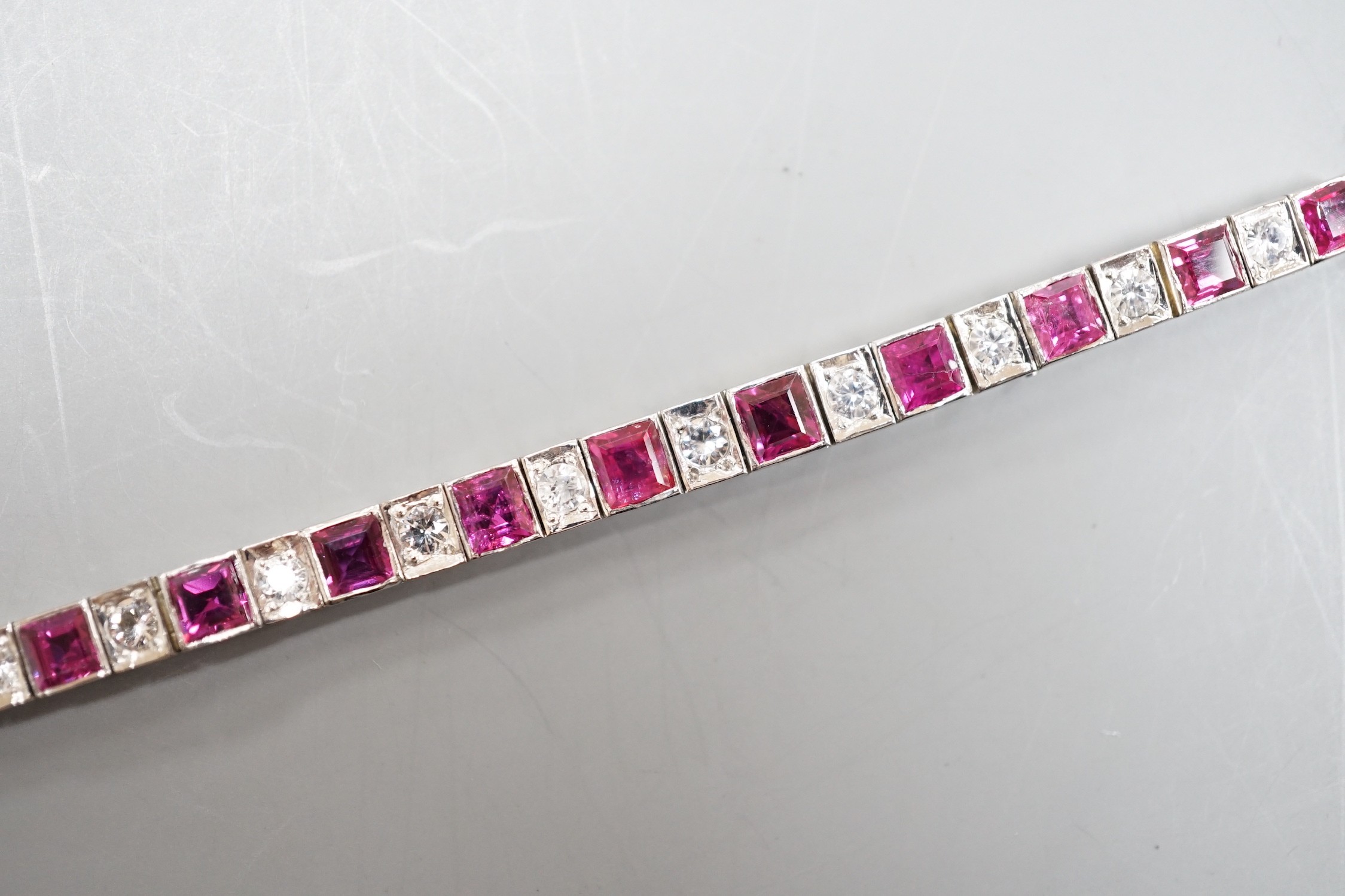 A white metal, ruby and white spinel set line bracelet, 16cm, gross weight 8.4 grams.